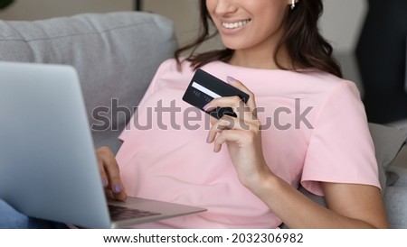 Close up crop panoramic view of happy ethnic woman shopping online on computer with credit card. Smiling millennial female client or buyer pay on internet on laptop use secure banking system.