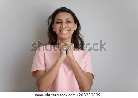 Headshot portrait of smiling Indian Arabic woman isolated on grey studio wall background posing. Profile picture of happy millennial middle eastern female feel excited overjoyed. Happiness concept.