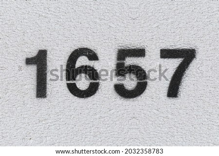 Black Number 1657 on the white wall. Spray paint. Number one thousand six hundred fifty seven.