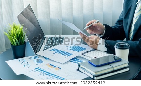 Businessman working on graph papers and laptops using income and expense calculators, accounts or financial auditors to make reports, calculations, home finance, investment, economy, savings or office Royalty-Free Stock Photo #2032359419