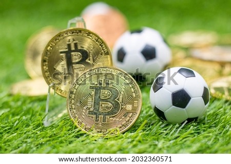 Bitcoin and Soccer Ball are on Green grass for gambling concept. Major Soccer Clubs in Europe Make it  as gateway into speculative cryptocurrency
