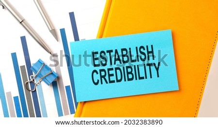 ESTABLISH CREDIBILITY text on sticker on yellow notebook with chart and pen