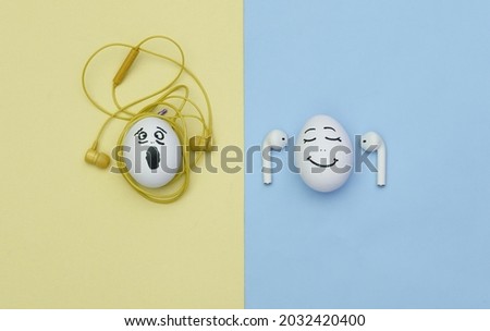 Humorous concept. Eggs with faces listening to music with wireless and wired tangled headphones. Modern technologies. Flat lay