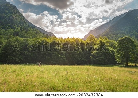 Young man trekking on the top of a green mountain enjoying the amazing landscape views during sunset. Paradise grass mountain. Lifestyle relax and freedom. The beauty of nature concept.