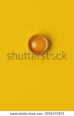 Fresh Easter one brown chicken broken egg with yolk on yellow background. Minimal Easter concept idea,negative space.