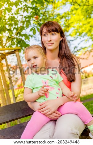 sitting in park younger mother with little girl