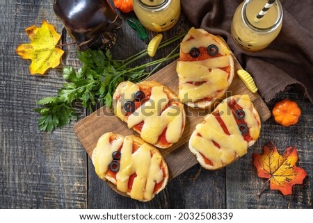 Halloween party food. Halloween mummies mini pizzas on a wooden table. Top view flat lay background. 