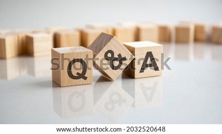 Q and A - an abbreviation of wooden blocks with letters on a gray background. Reflection of the Q and A caption on the mirrored surface of the table. Selective focus. Royalty-Free Stock Photo #2032520648