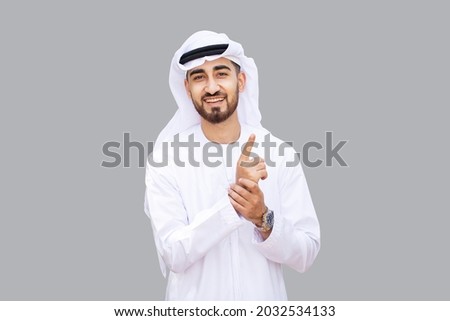 Young handsome Emirati business man in UAE traditional outfit showing a variety of hand gesture. Arabic ambitious mature businessman. Royalty-Free Stock Photo #2032534133