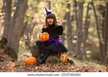 three little girls in witch costumes laugh, conjure, walk through the autumn forest with baskets for sweets in the shape of pumpkins. halloween concept, lifestyle . High quality photo