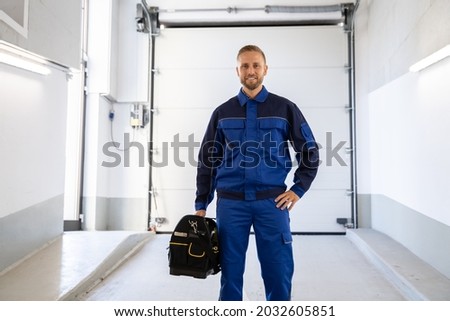 Garage Door Installation And Repair At Home. Contractor Man In House Royalty-Free Stock Photo #2032605851