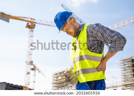 Engineer With Back Pain Injury After Accident At Construction Site Royalty-Free Stock Photo #2032605926