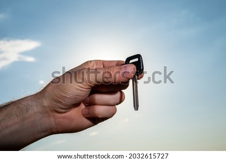 Female handing over keys on dramatic clouds and sky with sun rays behind.