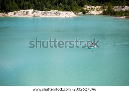 A girl in a dress floats on a glanders board on a pond with bright turquoise water. Warm summer day for travel