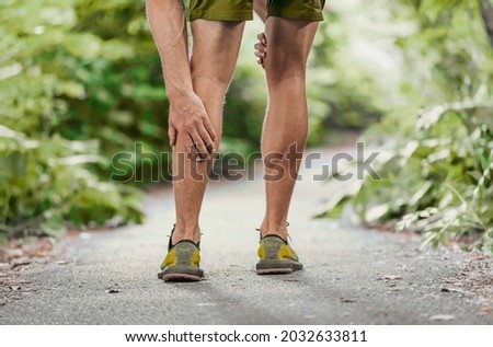 Muscle pain sports injury runner man touch leg calf in pain. Painful legs athlete massaging sore calf muscles during running training outdoor. Royalty-Free Stock Photo #2032633811