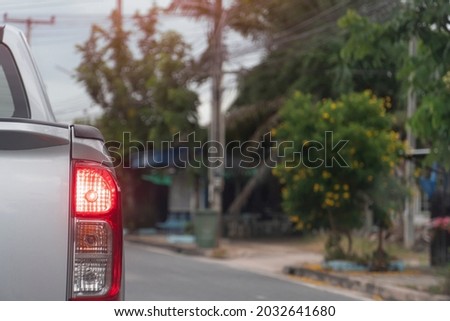 Rear side of silver pick-up car driving on the asphalt road in the city. During daytime.  with open brake light.