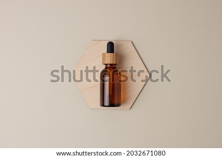 Cosmetic bottle with a wooden hexagon on pastel beige background. Flat lay, copy space