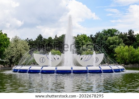 Landscape with the lake, decorative fountain and vivid green trees in Drumul Taberei Park (Parcul Drumul Taberei) also known as Moghioros Park, in Bucharest, Romania, in a sunny spring day
