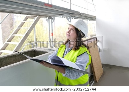 experienced woman architect, constructor engineer in protective white helmet controls the object at the construction site for the renovation of buildings, civil engineering concept Royalty-Free Stock Photo #2032712744