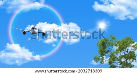 White clouds, flying airplane and round rainbow in the clear sunny sky. The sun shining through the green tree branches. stretch ceiling picture