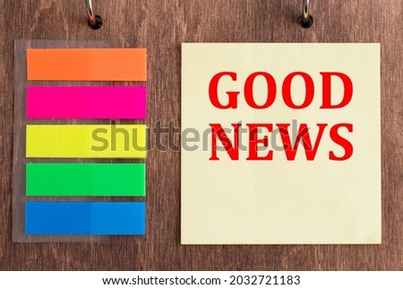 GOOD NEWS written on yellow note card on wooden background