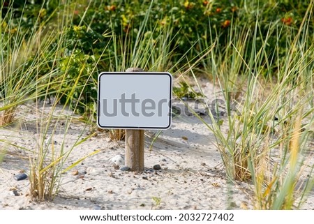 Empty sign board with dune landscape in background