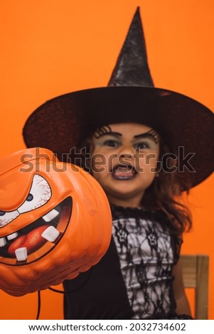 Little Caucasian witch with her Halloween pumpkin in her hand