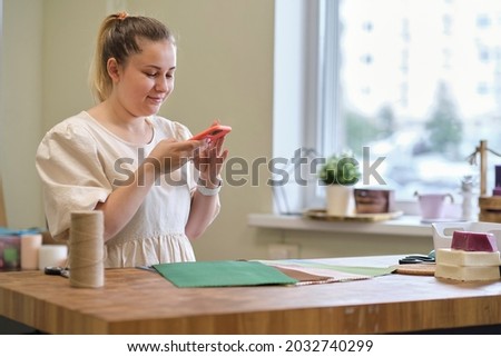woman entrepreneur photographs her work for social networks. A woman makes candles for sale in her workshop. Social media promotion concept, internet marketing