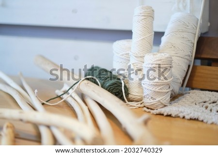 Balls of white yarn and rustic sticks on table. Good for macrame and handicrafts banners. natural decoration concept.