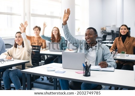 Presentation, Convention Concept. Portrait of smiling international people participating in seminar at modern office, raising hands up to ask question or to volunteer, diverse group sitting at tables Royalty-Free Stock Photo #2032749785