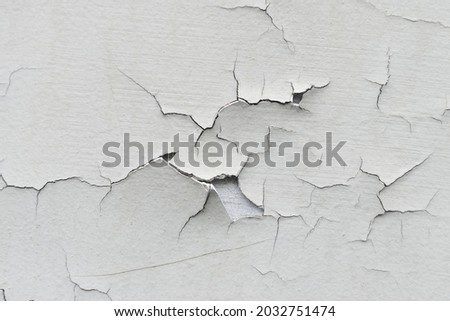 Close-up. Badly fixed building facade wall covered with cracks in stucco and paint. Missing patch of paint in the middle; crack with flappy peeling edges. Royalty-Free Stock Photo #2032751474