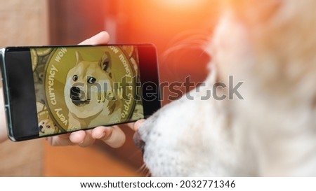 Dogecoin cryto with A dog watching DOGE digital cryptocurrency in smartphone on internet exchange market. Business technology concept.