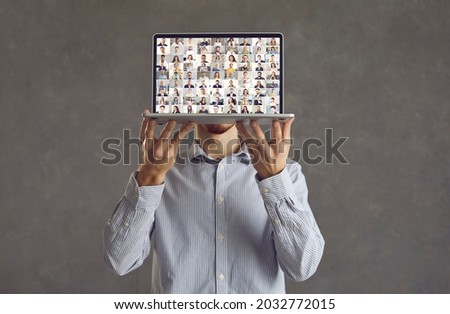 Modern technology and online business communication: Man showing laptop computer screen during video conference call with lots of international participants, studio shot, isolated on grey background