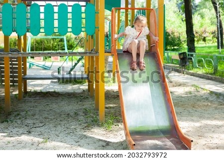 Little girl are playing in the park. The child slides down the children's slide.