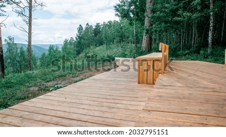 View of the observation deck with a beautiful bench against the backdrop of the forest