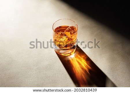 Glass of elegant whiskey with ice cubes on a bar counter with dark moody atmosphere. Drink art concept. Royalty-Free Stock Photo #2032810439