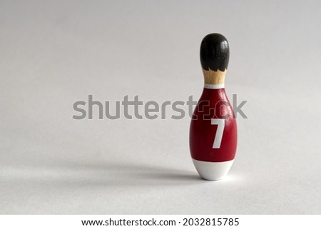 rear view of a wooden puppet in the shape of a bowling pin with a number seven shirt