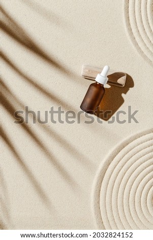 Anti aging serum with collagen and peptides in dark glass bottle with dropper on sandy background with sunlight and shadow from palm leaf. Skincare essence for beautiful healthy skin. Top view. Royalty-Free Stock Photo #2032824152