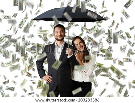 young smiley couple with black umbrella standing under money rain