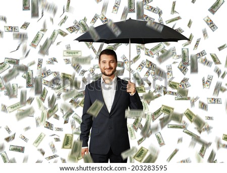 successful smiley businessman with black umbrella standing under money rain