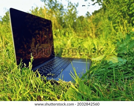Laptop close-up on the grass in nature. The concept of technology and nature. Space for the text.