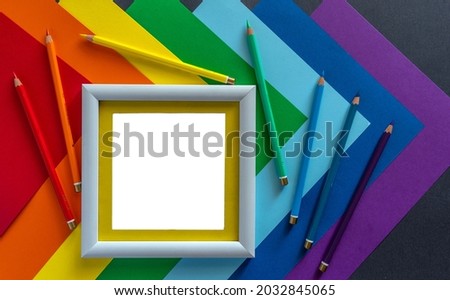 Sheets of multi-colored paper, colored pencils to match the paper and a photo frame for an image or text. Colors of rainbow. LGBT community symbol.
