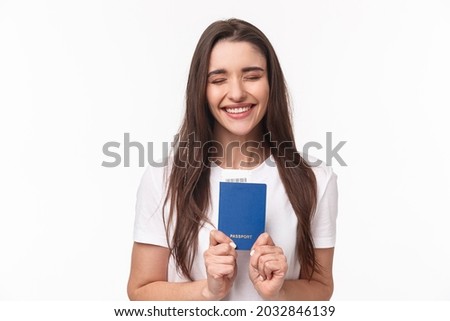Travelling, holidays, summer concept. Portrait of cheerful happy, laughing girl close eyes and smiling enthusiastic, receive her pasport to travel abroad, finally sitting in airport ready for journey Royalty-Free Stock Photo #2032846139