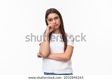 Waist-up portrait of bored, uninterested young brunette female in glasses, feel tired or sleepy, listening to boring conversation, lean on hand look reluctant with lack of interest, white background