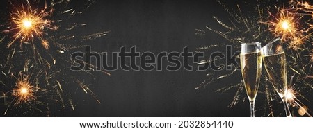 HAPPY NEW YEAR 2022 - Festive silvester background panorama banner long - Golden yellow firework and two champagne classes toasting on black night texture Royalty-Free Stock Photo #2032854440