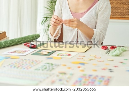 Hands of woman making stars out of colorful paper stripes when creating greeting cards at home