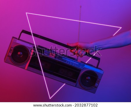 Hand holding retro radio tape recorder. in blue-red neon gradient light with triangle. Pop culture. 80s retro wave