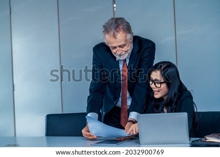 Senior executive manager and young businesswoman working in meeting room in the office. The woman is secretary or translator. International business language translation concept.