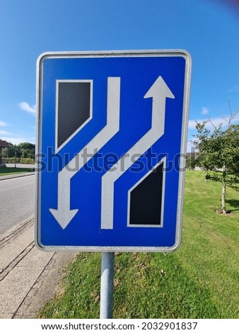 A blue, black and white road sign
