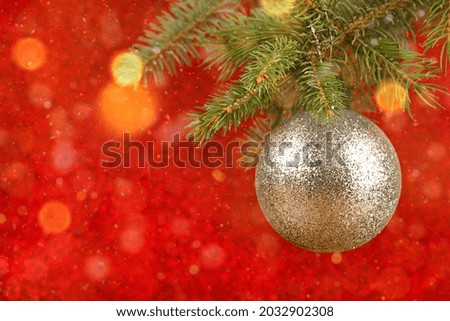 festive red background christmas tree branch with gold ornament
